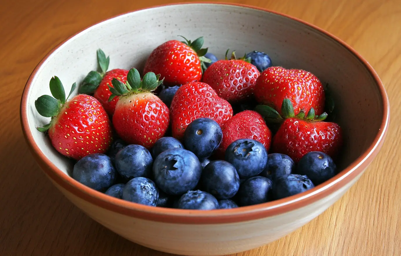 A bowl of strawberries and blueberries, placed on the table, is fresh and bright in color. The photo was taken from above with clear details. It's a close-up shot that showcases various fruits. This scene conveys freshness and vitality. A bowl of strawberries and blueberries, placed on the table, is fresh and bright in color. The photo was taken from above with clear details. It's a close-up shot that showcases various fruits. This scene conveys freshness and vitality.