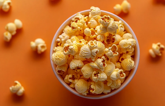 A bowl of popcorn on an orange background, high-resolution photography, minimalist style, top view.